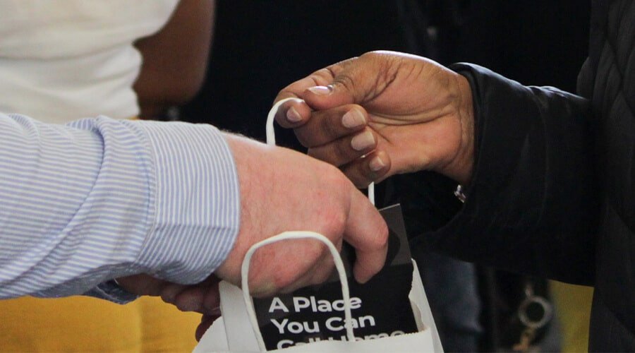 Church Volunteer handing first time guest a gift